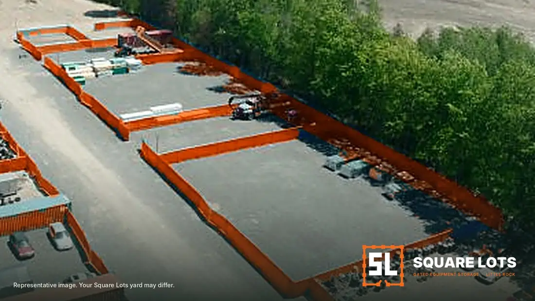 Fenced equipment lots with orange privacy screen along a gravel drive aisle